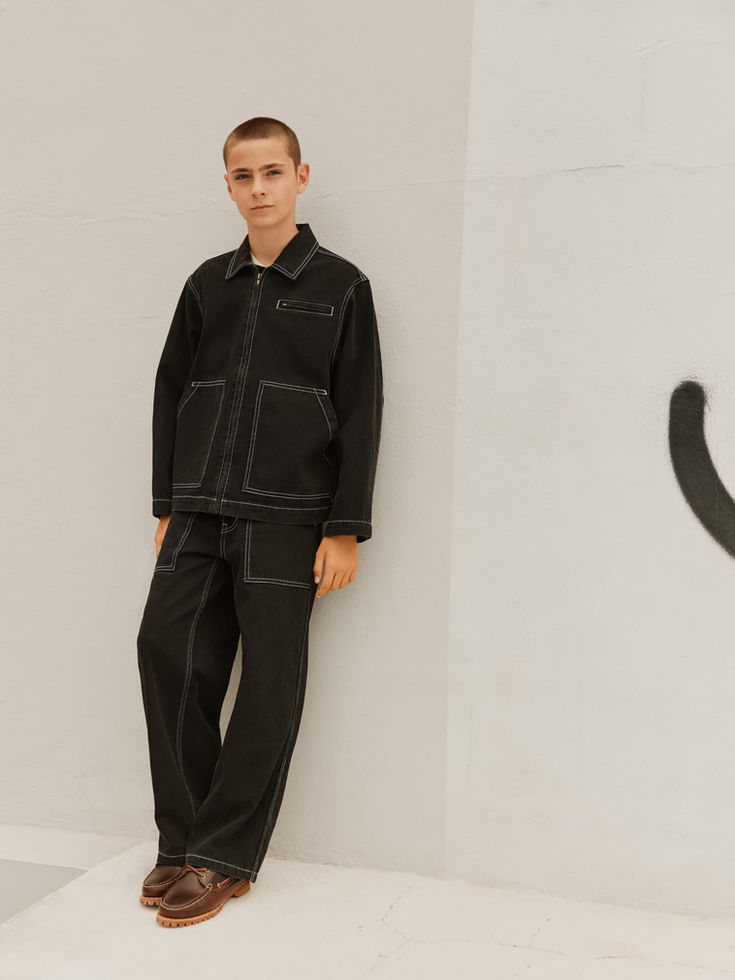 Child standing indoors wearing the black jacket and matching pants.