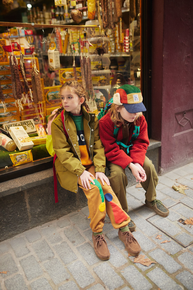Children sitting down wearing the reversible multicolor jacket.