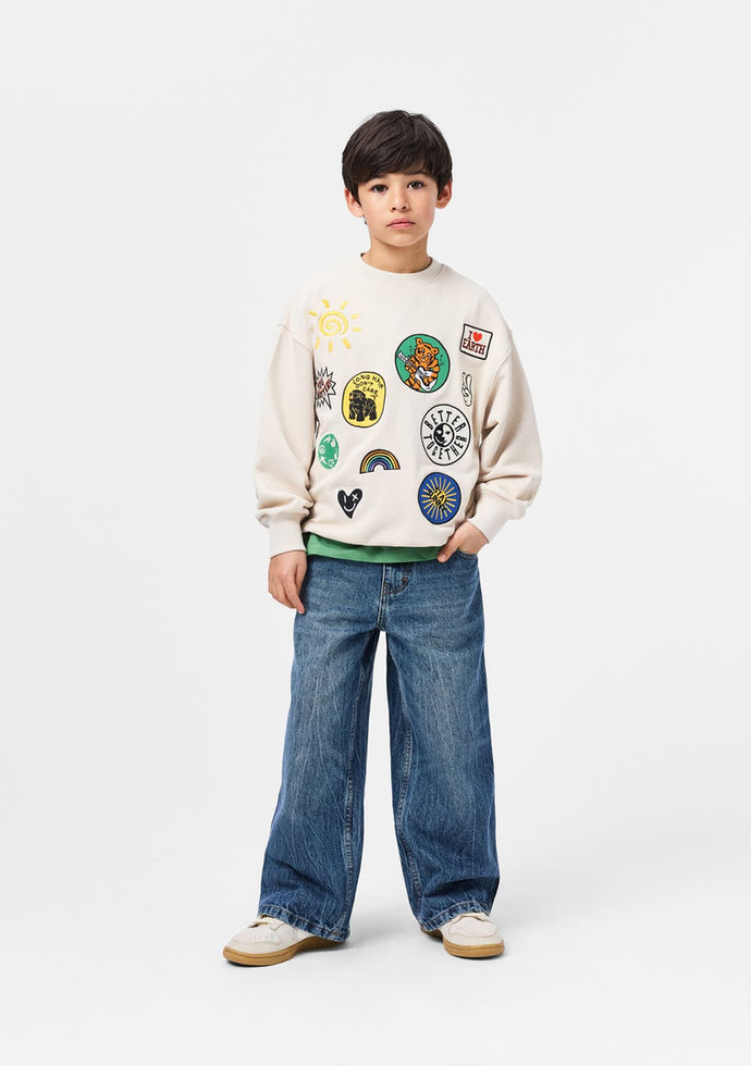 Child standing and facing forward, wearing the sweatshirt with jeans.