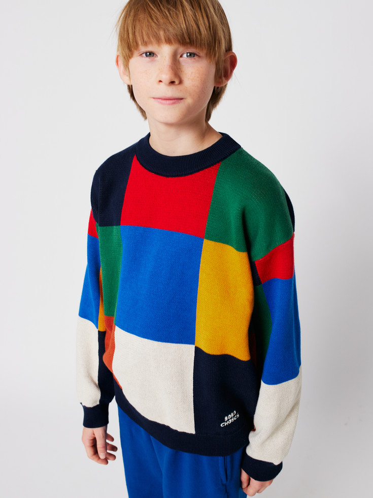 Model wearing color block jumper with large tile-style squares in vibrant shades