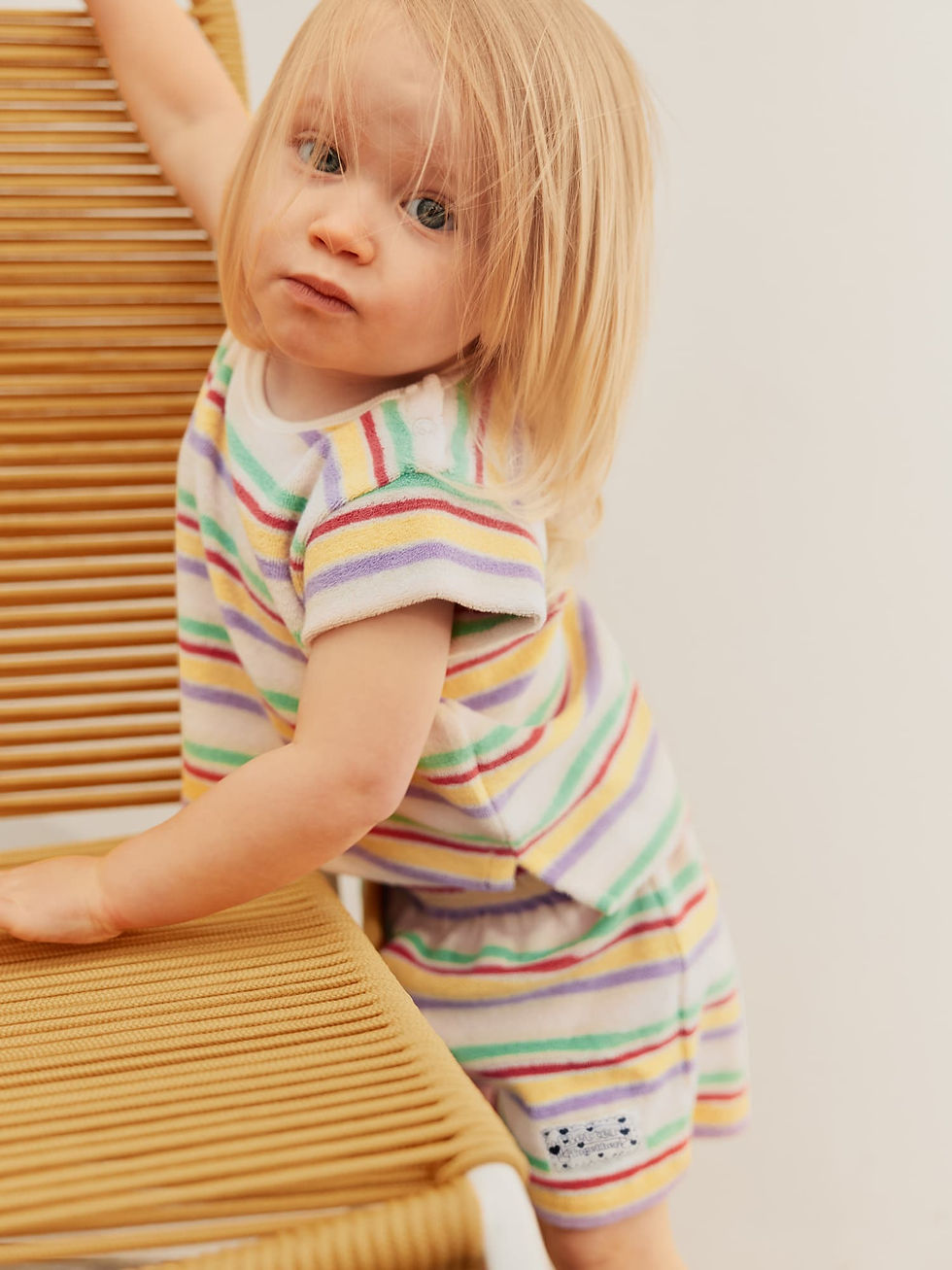Toddler leaning forward, wearing the striped T-shirt and matching shorts.