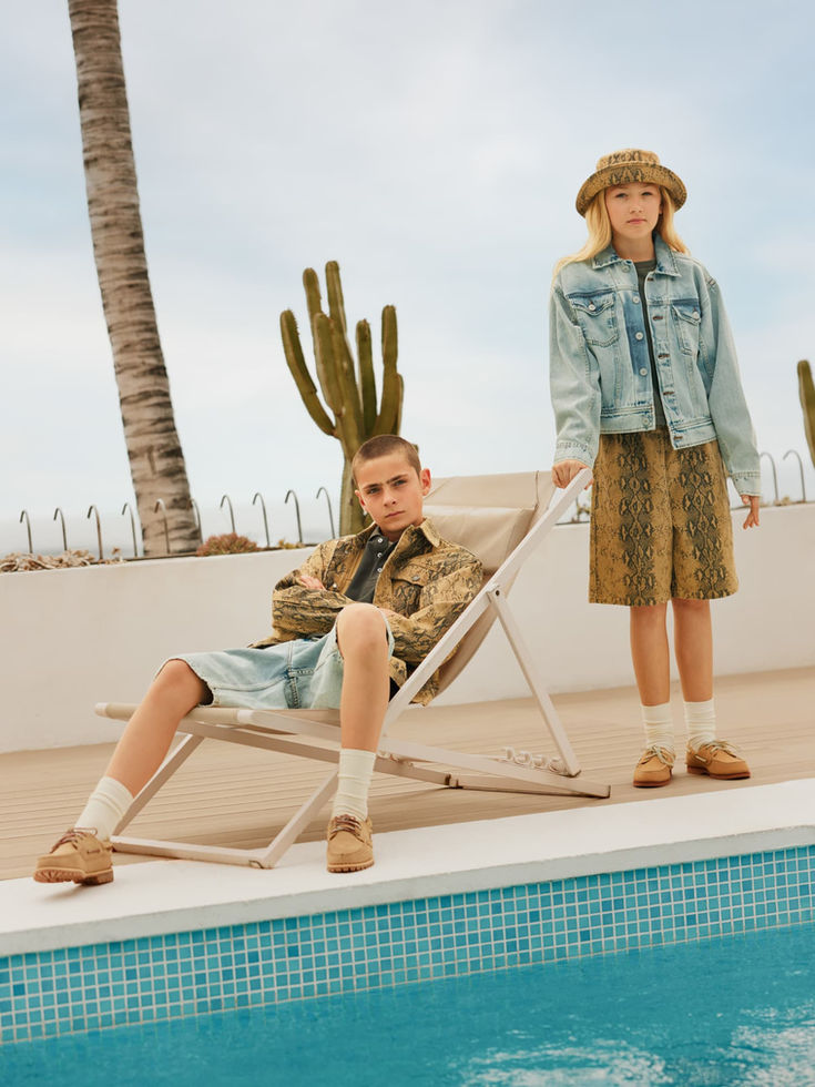 Children sitting outdoors by a pool, wearing casual outfits including the denim jacket.
