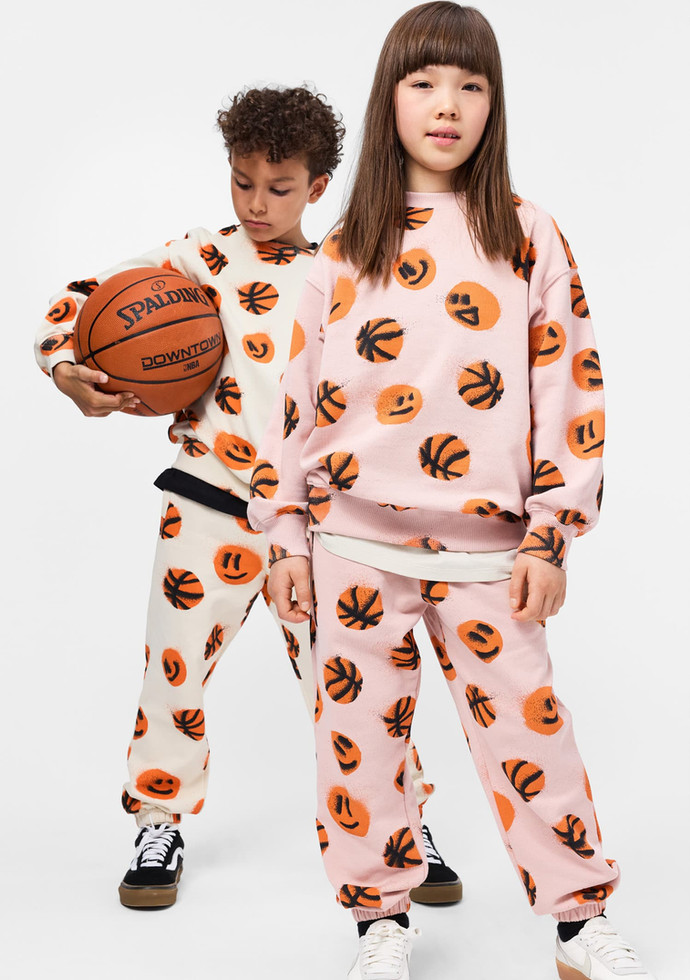 Child wearing the matching sweatshirt and pants set while holding a basketball.