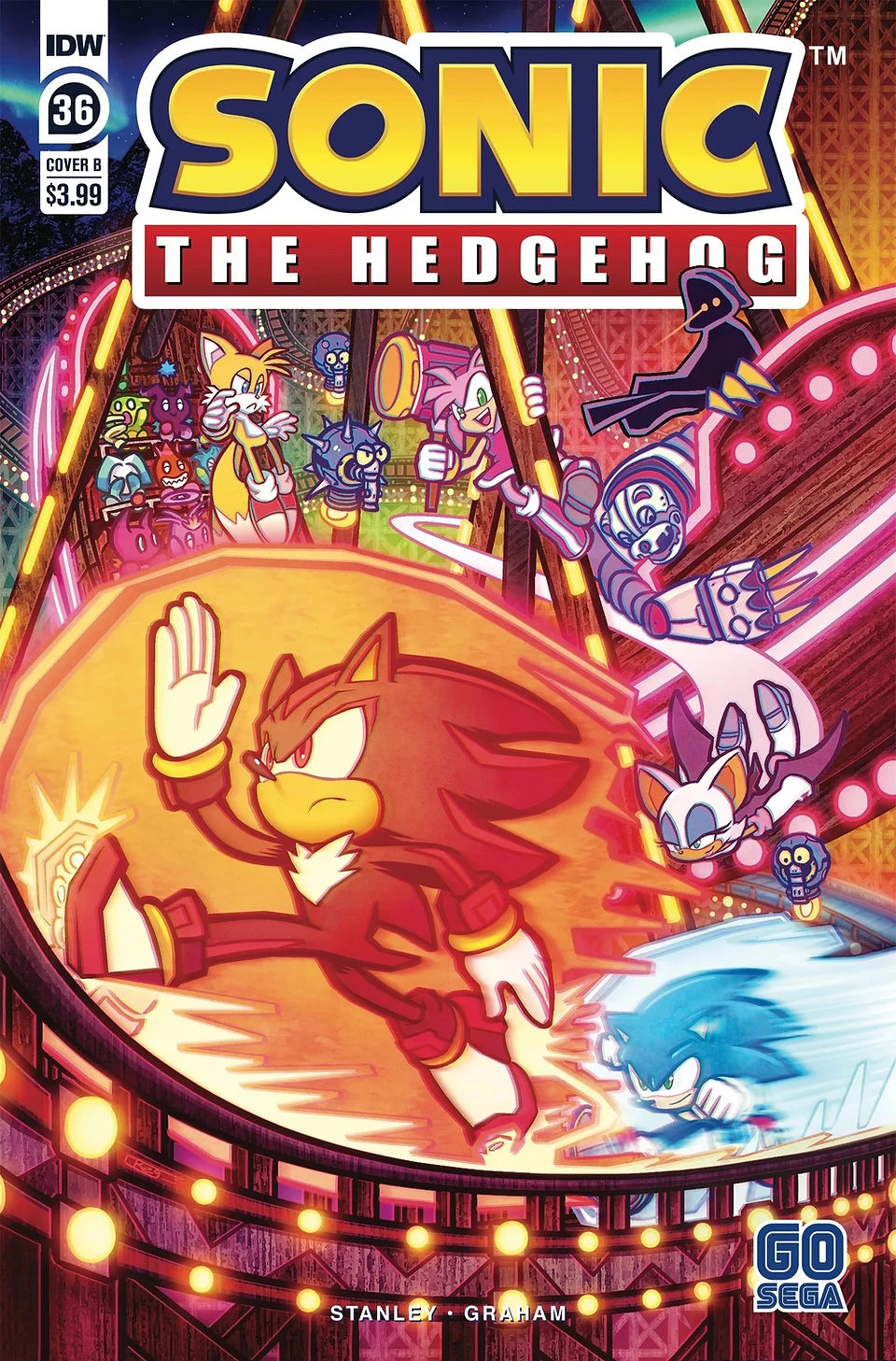 Cover of Sonic The Hedgehog #36 (Reggie Graham variant) shows Shadow and Sonic running along a metal track, Behind them is an amusement park showing a roller coaster track and a swinging boat ride which has chaos on it. Amy is holding on to a support beam with her hammer in hand, Tails is flying near a couple badniks. Rouge is flying in towards Sonic while Snowy takes a swipe at her. A mysterious hooded figure stands in the background.