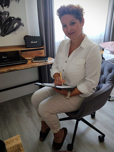 Ich sitze auf einem Stuhl im Studio und habe die Mappe zum Präsentieren der Leistungen und Beratungen zur Hand.