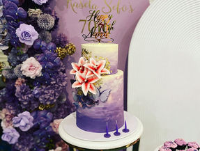 Two tiered white and purple birthday cake with flowers
