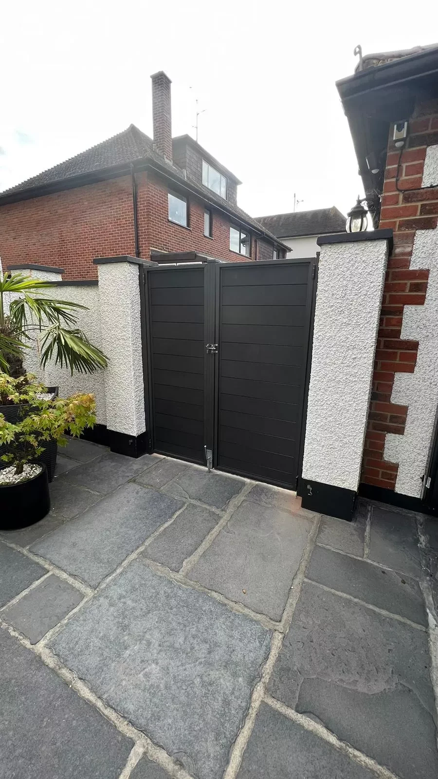 Charcoal double composite gates between 2 white pillars