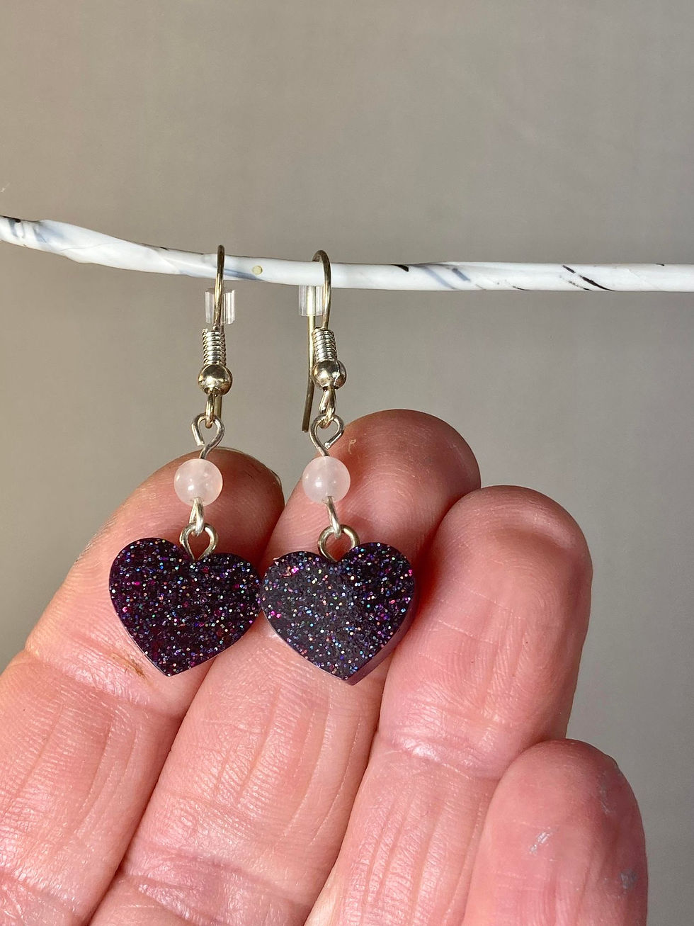 Thumbnail: heart earrings front view in hand for size reference