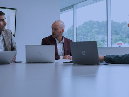 trois hommes d'affaire discutent autour d'une table avec leurs ordinateurs portables