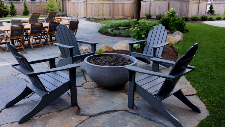Flagstone fire pit terrace with black Adirondack chairs — O'Connor Design Build, Rhode Island