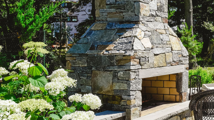 Stone outdoor fireplace with limelight hydrangea in bloom — O'Connor Design Build, Rhode Island