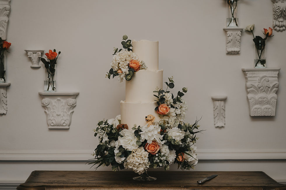 A wedding cake dressed in flowers that match the flowers decorating The Reception Room