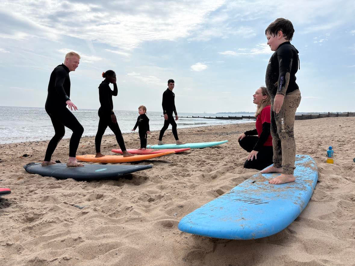 Group surf lesson, learning how to stand on a surf board on the beach