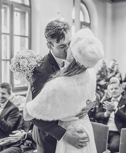 Couple s'embrassant pendant leur mariage devant leurs invités