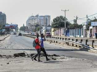 Jovens atravessam rua danificada em Moçambique