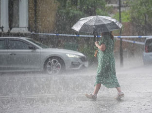 Uma pessoa caminha na chuva por Kentish Town
