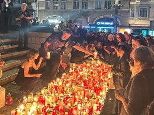 Pessoas acendem diversas velas ao chão em luto após tiroteio
