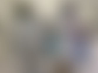 Profissional de saúde usando jaleco branco e máscara facial realiza demonstração do uso de um ventilador pulmonar em uma sala hospitalar.