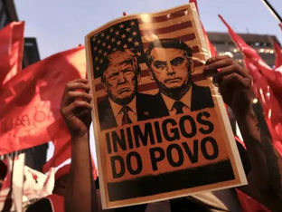 Protestante segura cartaz com imagens de Trump e Bolsonaro escrita 'Inimigos do Povo'