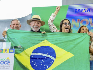 Lula segura bandeira do Brasil em mãos junto de mulher sorridente
