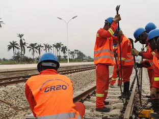 A imagem retrata trabalhadores da construção civil envolvidos na manutenção ou construção de uma linha férrea.