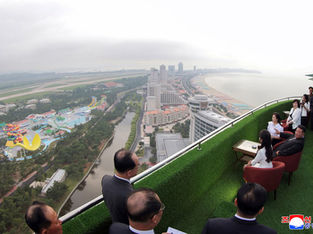 A imagem mostra a Zona Turística Costeira de Wonsan-Kalma, na Coreia do Norte, com Kim Jong Un e outros oficiais em um terraço com vista para o complexo.