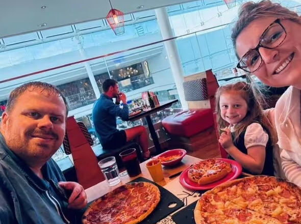 Pai aparece em foto com sua esposa e filha em mesa com pizzas