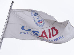 A imagem mostra a bandeira da Agência dos Estados Unidos para o Desenvolvimento Internacional (USAID).