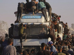 Palestinos sobem em um caminhão carregado de alimentos e ajuda humanitária, enquanto ele se move pelo corredor Morag, na Faixa de Gaza.