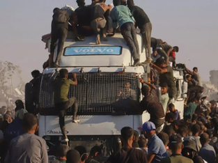 Palestinos sobem em um caminhão carregado de alimentos e ajuda humanitária, enquanto ele se move pelo corredor Morag, na Faixa de Gaza.