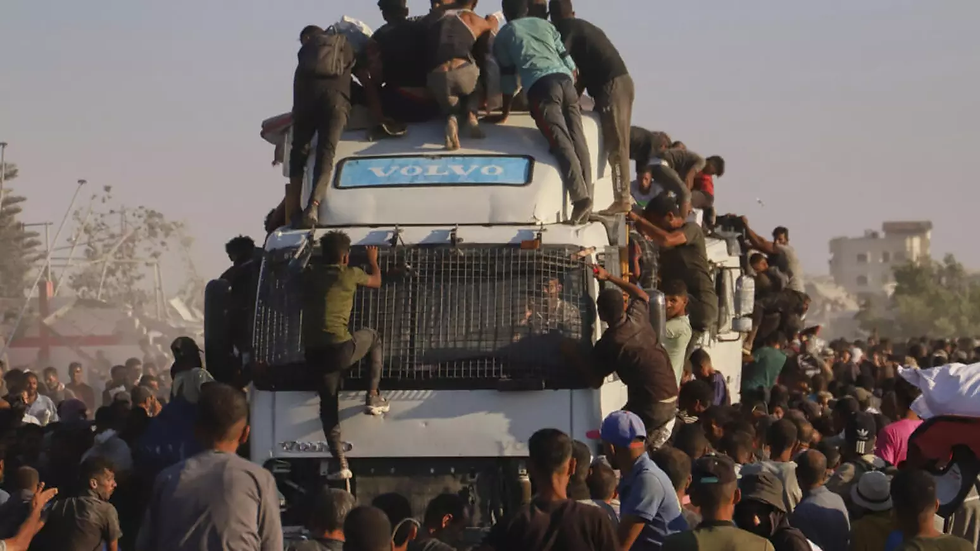 Palestinos sobem em um caminhão carregado de alimentos e ajuda humanitária, enquanto ele se move pelo corredor Morag, na Faixa de Gaza.