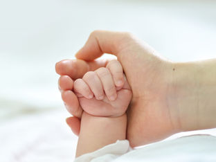Mão de mãe segura mão de bebé