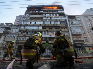 Bombeiros posicionados a frente à edifício incendiado