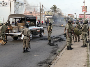 Imagem de rua com focos de incêndio e policiais estão a postos no local