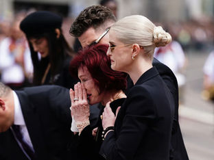 Sharon e Kelly observam as mensagens e homenagens florais deixadas no banco da Ponte Black Sabbath na Broad Street