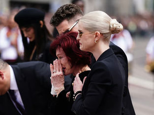 Sharon e Kelly observam as mensagens e homenagens florais deixadas no banco da Ponte Black Sabbath na Broad Street