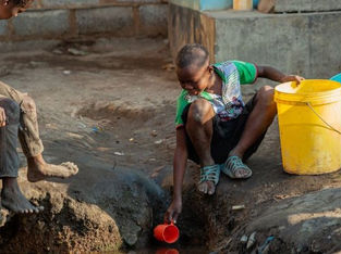 criança pega água em córrego possivelmente contaminado