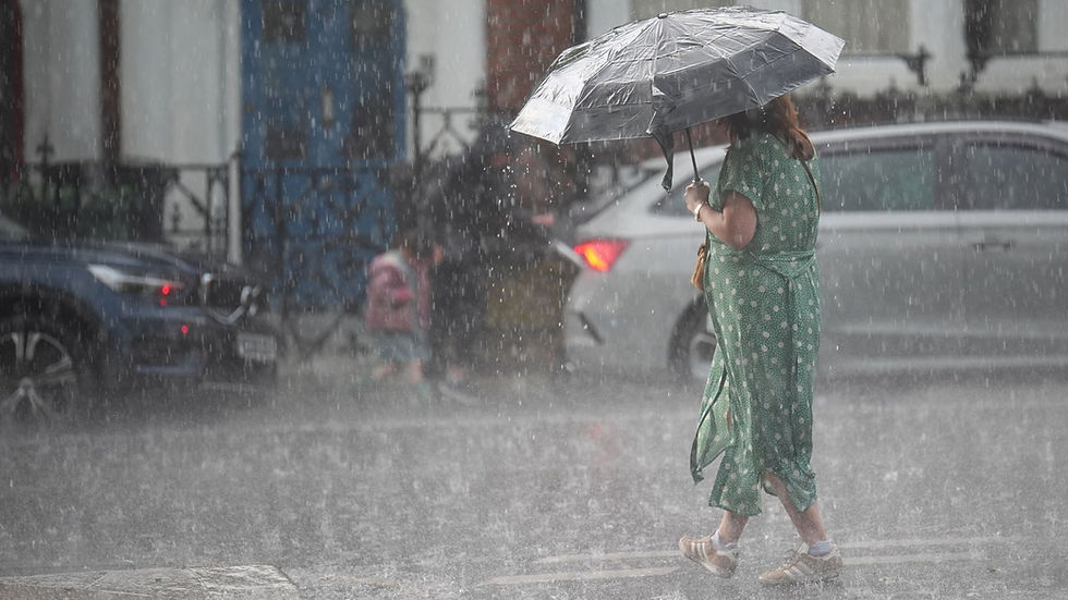 Mulher anda em chuva com guarda-chuvas