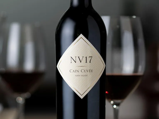 Garrafa de vinho e taças com vinho ao fundo