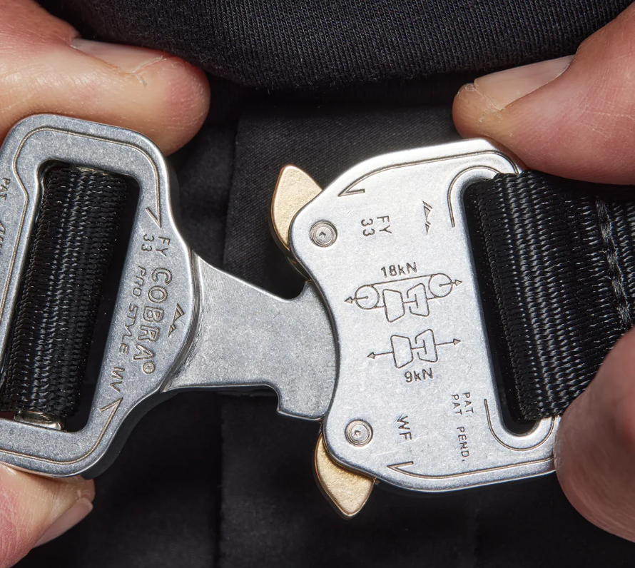 Hands adjusting Cobra buckle, showing strength markings.