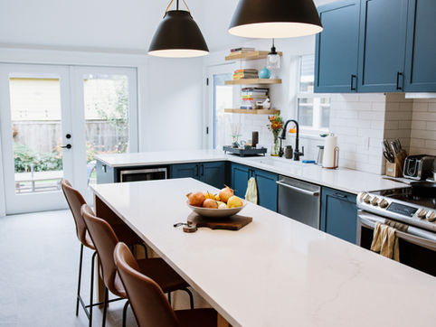 Blue and white kitchen with dark fixtures and large island with seating create a welcoming social environment.