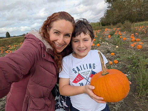 Smiling Mom and son holding a pumpkin in a pumpkin patch