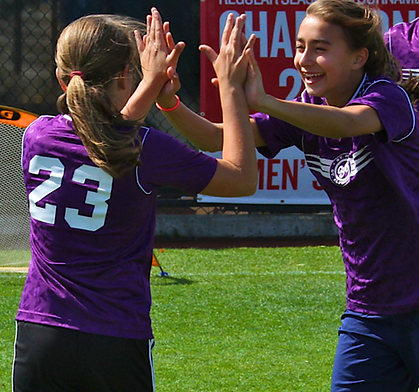 Middle School female soccer players in purple uniform smiling and giving a High-five