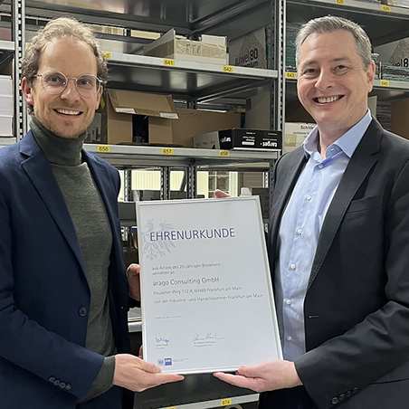 Daniel Stöckel und Dr. Matthias Schroder halten zusammen erfreut die Urkunde für das 25-jährige Bestehen der arago Consulting hoch.