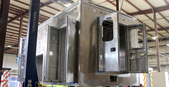 Rear driver side view of Type I ambulance for Washington #2697 on welding and fabrication lift.