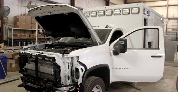 Front driver side corner view of white Type I ambulance in box prep.