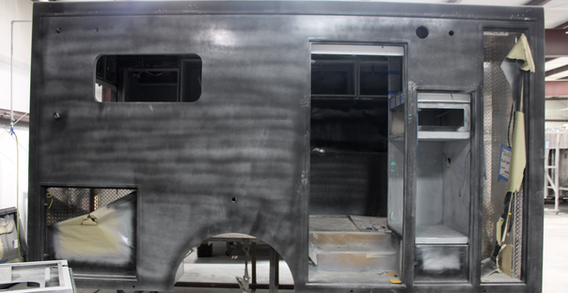 Curbside view of Type III ambulance after initial primer in paint and body prep.