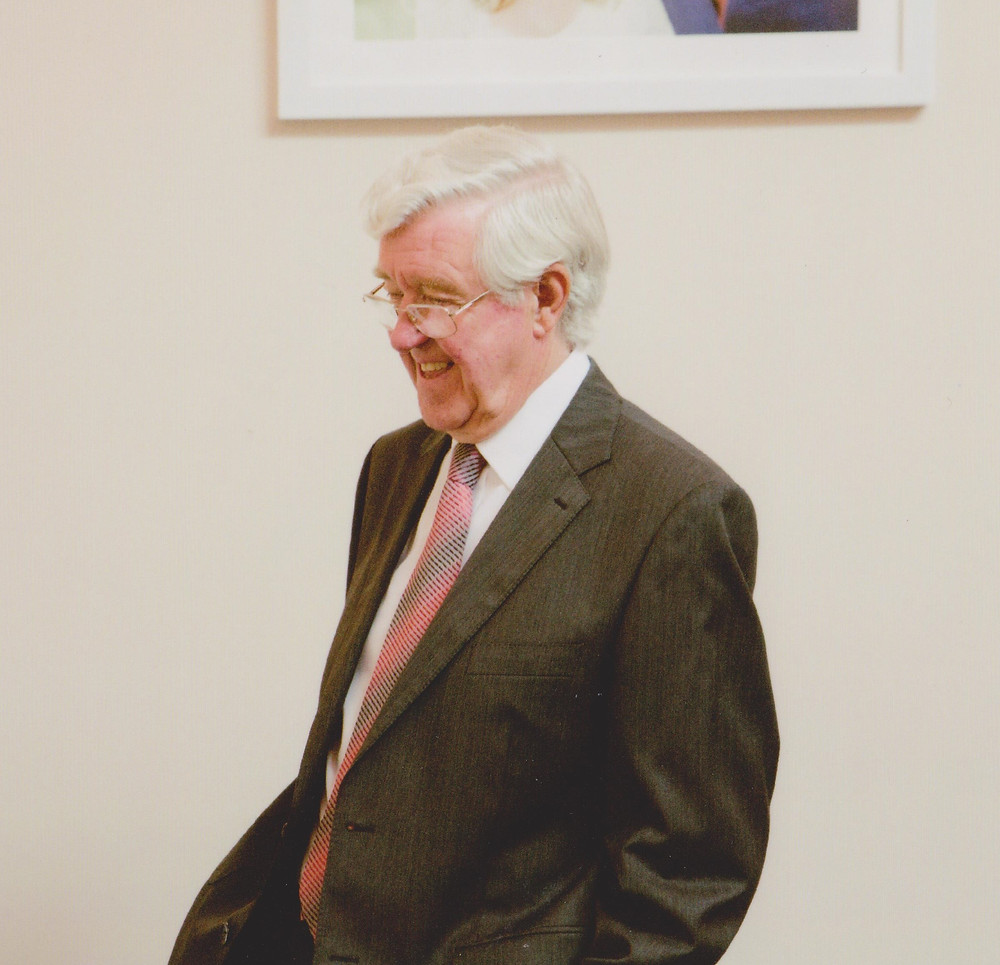 Grey haired man in suit smiling