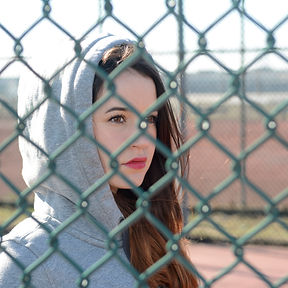 girl looking through chain fence