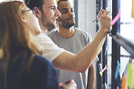 A small business team working on an idea together by writing notes on a board